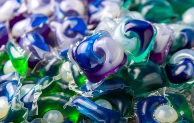 Koyu dokulu arka planda çamaşır kapsülleri. Çamaşır makineleri için sıvı çamaşır tozu içeren kapsüller. Yıkama ve temizlik kavramı. Boşluğu kopyala.