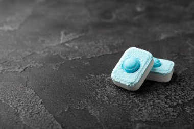 Siyah doku arka planında su yumuşatıcı haplar. Çamaşır makineleri ve bulaşık makineleri için kapsüller, kireçlenme ölçeğini engelliyor. Kopyalanacak yer.