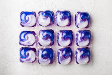 Çamaşır deterjanı yıkamak için kapsüller çamaşır makinesinde çamaşır yıkamak için kapsüller beyaz çimento arka planında. Temizlik kavramı. Çamaşır makinesi için sıvı deterjanlı kapsüller..