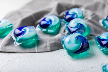 Çamaşır kapsülleri ve mutfak havlusu beyaz mermer arka planda. Çamaşır makinesinde çamaşır yıkamak için deterjan. Saflık kavramı. Metin için yer.