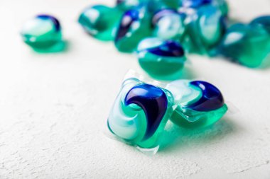 Çamaşır deterjanı yıkamak için kapsüller çamaşır makinesinde çamaşır yıkamak için kapsüller beyaz çimento arka planında. Temizlik kavramı. Çamaşır makinesi için sıvı deterjanlı kapsüller..