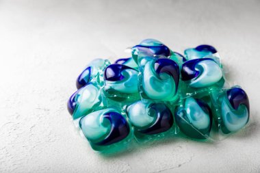 Çamaşır deterjanı yıkamak için kapsüller çamaşır makinesinde çamaşır yıkamak için kapsüller beyaz çimento arka planında. Temizlik kavramı. Çamaşır makinesi için sıvı deterjanlı kapsüller..