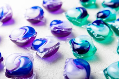 Çamaşır deterjanı yıkamak için kapsüller çamaşır makinesinde çamaşır yıkamak için kapsüller beyaz çimento arka planında. Temizlik kavramı. Çamaşır makinesi için sıvı deterjanlı kapsüller..