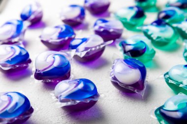 Çamaşır deterjanı yıkamak için kapsüller çamaşır makinesinde çamaşır yıkamak için kapsüller beyaz çimento arka planında. Temizlik kavramı. Çamaşır makinesi için sıvı deterjanlı kapsüller..