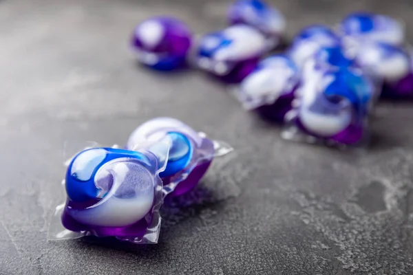 Koyu dokulu arka planda çamaşır kapsülleri. Çamaşır makineleri için sıvı çamaşır tozu içeren kapsüller. Yıkama ve temizlik kavramı. Boşluğu kopyala.