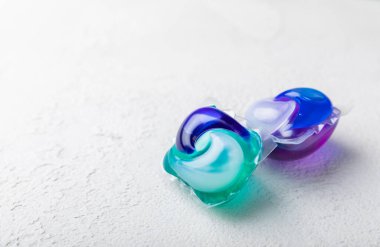 Çamaşır deterjanı yıkamak için kapsüller çamaşır makinesinde çamaşır yıkamak için kapsüller beyaz çimento arka planında. Temizlik kavramı. Çamaşır makinesi için sıvı deterjanlı kapsüller..