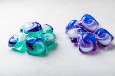 Çamaşır deterjanı yıkamak için kapsüller çamaşır makinesinde çamaşır yıkamak için kapsüller beyaz çimento arka planında. Temizlik kavramı. Çamaşır makinesi için sıvı deterjanlı kapsüller..