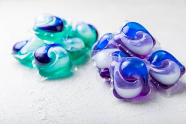 Çamaşır deterjanı yıkamak için kapsüller çamaşır makinesinde çamaşır yıkamak için kapsüller beyaz çimento arka planında. Temizlik kavramı. Çamaşır makinesi için sıvı deterjanlı kapsüller..