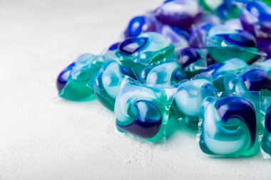 Çamaşır deterjanı yıkamak için kapsüller çamaşır makinesinde çamaşır yıkamak için kapsüller beyaz çimento arka planında. Temizlik kavramı. Çamaşır makinesi için sıvı deterjanlı kapsüller..