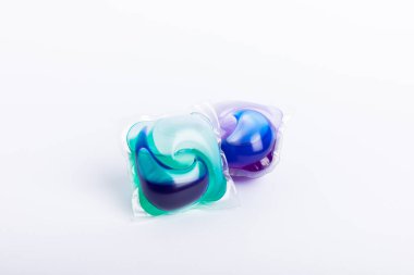 Çamaşır deterjanı yıkama kapsülleri çamaşır makinesinde çamaşır yıkamak için beyaz arka planda izole edilmiş. Saflık kavramı. Metin için yer.