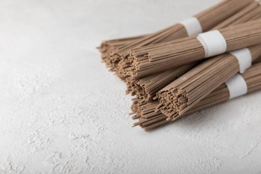 Beyaz arka planda karabuğday sobalı makarna. Çiğ erişte. Glütensiz yemek için gerekli malzemeler. Kurutulmuş karabuğday sobalı erişte. Geleneksel Japon yemekleri. Sağlıklı yiyecekler. Kopyalanacak yer.