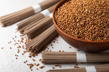 Kasede karabuğday lapası ve beyaz mermer arka planda karabuğday sobalı erişte. Çiğ karabuğday. Glüten içermeyen mısır gevreği. Sağlıklı yiyecekler. Kopyalanacak yer.