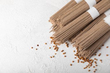 Beyaz arka planda karabuğday sobalı makarna. Çiğ erişte. Glütensiz yemek için gerekli malzemeler. Kurutulmuş karabuğday sobalı erişte. Geleneksel Japon yemekleri. Sağlıklı yiyecekler. Kopyalanacak yer.