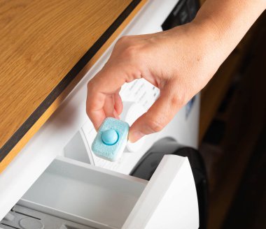 Suyu yumuşatmak ve çamaşır makinesindeki kireçtaşını önlemek için kapsül. Yakın plan. Çamaşır yıkıyorum. Yıkama ve temizleme kavramı