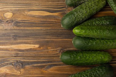 Kahverengi ahşap üzerinde taze salatalıklar. Vejetaryen organik sebzeler. Salata için. Sağlıklı yiyecek. Boşluğu kopyala. Metin için yer