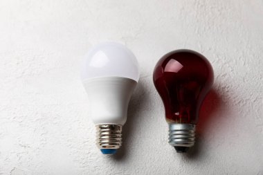 Elektrik ampulleri. Enerji verimliliği kavramı. LED lamba parlak lambaya karşı. Gri çimento arka planında kompozisyon. Ekonomik ve çevre dostu bir ampul kavramı kullan.