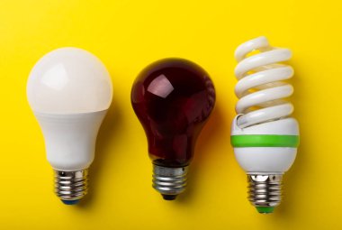 Elektrik ampulleri. Enerji verimliliği kavramı. LED lamba parlak lambaya karşı. Sarı arka planda kompozisyon. Ekonomik ve çevre dostu bir ampul kavramı kullan.