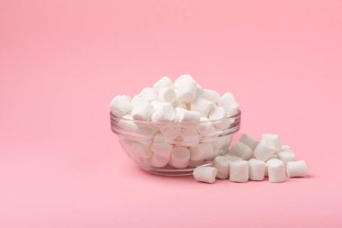 Cam bir kasede pembe arka planda şekerlemeler. Beyaz şekerleme düz yerde yatıyordu. Atıştırmalık tatlı ve atıştırmalıklar. Şekerleri yakından çiğniyor. Uzayı kopyala Mesaj için yer. Kış yemekleri konsepti.