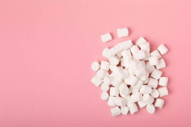 Pembe arka planda gevşek şekerleme. Beyaz şekerleme düz yerde yatıyordu. Atıştırmalık tatlı ve atıştırmalıklar. Şekerleri yakından çiğniyor. Uzayı kopyala Mesaj için yer. Kış yemekleri konsepti.