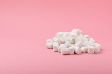 Pembe arka planda gevşek şekerleme. Beyaz şekerleme düz yerde yatıyordu. Atıştırmalık tatlı ve atıştırmalıklar. Şekerleri yakından çiğniyor. Uzayı kopyala Mesaj için yer. Kış yemekleri konsepti.