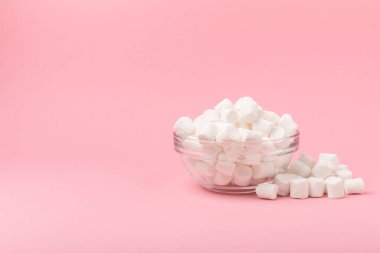 Cam bir kasede pembe arka planda şekerlemeler. Beyaz şekerleme düz yerde yatıyordu. Atıştırmalık tatlı ve atıştırmalıklar. Şekerleri yakından çiğniyor. Uzayı kopyala Mesaj için yer. Kış yemekleri konsepti.