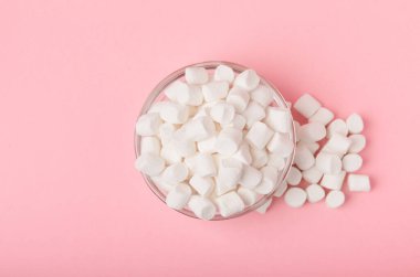 Cam bir kasede pembe arka planda şekerlemeler. Beyaz şekerleme düz yerde yatıyordu. Atıştırmalık tatlı ve atıştırmalıklar. Şekerleri yakından çiğniyor. Uzayı kopyala Mesaj için yer. Kış yemekleri konsepti.