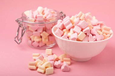 Seramik bir kasede şekerleme ve pembe bir arka planda cam kavanoz. Yakın plan çilek aromalı şeker, partiler için abur cubur, kahve ve kakao. Kış yiyecekleri konsepti için yer..