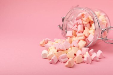 Pembe arka planda cam bir kavanozda lokum. Meyve aromalı tatlılar. Çilekli lokum. Uzayı kopyala. Metin için yer