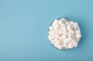 Mavi arka plandaki kaselerde marşmelovlar. Yakın plan sakızlar, partiler için abur cuburlar, kahve ve kakao için atıştırmalıklar. Kış yiyecekleri konsepti..