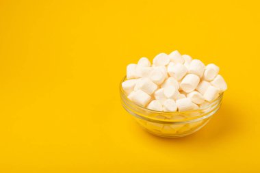 Sarı arka planda bir kasede şekerlemeler. Atıştırmalık tatlı ve atıştırmalıklar. Yakın plan şekerleme. Kopya için yer..