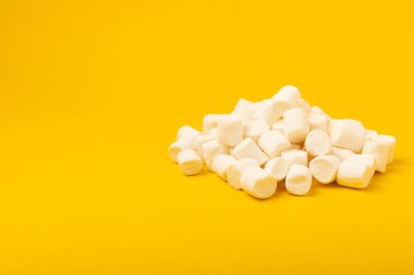 Sarı arka planda gevşek şekerlemeler. Beyaz şekerleme düz yerde yatıyordu. Atıştırmalık tatlı ve atıştırmalıklar. Şekerleri yakından çiğniyor. Uzayı kopyala Mesaj için yer. Kış yemekleri konsepti.