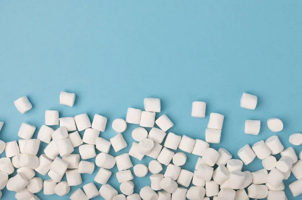 蓝色背景上的松软棉花糖 白色棉花糖平坦地躺着 糖果和零食当小吃 嚼糖特写 复制空间 文字的位置 冬季食品概念 — 图库照片