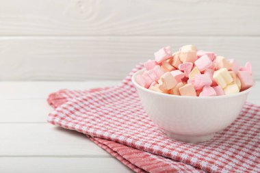 Çilekli şekerlemeler cam bir kasede beyaz desenli bir arka planda, rustik bir peçeteyle. Kapalı sakızlar, partiler için atıştırmalıklar, kahve ve kakao için atıştırmalıklar. Kış yiyecekleri konsepti. Metin için yer. Kopya için yer..