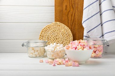 Bir sürü farklı marşmelov kaselerde ve kavanozlarda beyaz desenli bir ahşap üzerinde. Beyaz ve meyveli lokum. Atıştırmalık tatlı ve atıştırmalıklar. Şekerleri yakından çiğniyor. Uzayı kopyala Metin için yer.