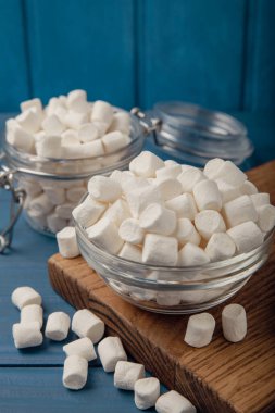 Mavi desenli ahşap üzerinde lokum. Cam bir kasede beyaz şekerlemeler ve masada bir kavanoz. Atıştırmalık şeker ve atıştırmalıklar. Şekerleri yakından çiğniyor. Uzayı kopyala Mesaj için yer. Kış yemekleri konsepti.