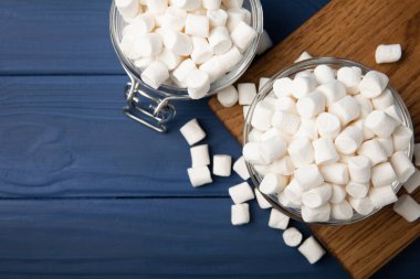 Mavi desenli ahşap üzerinde lokum. Cam bir kasede beyaz şekerlemeler ve masada bir kavanoz. Atıştırmalık şeker ve atıştırmalıklar. Şekerleri yakından çiğniyor. Uzayı kopyala Mesaj için yer. Kış yemekleri konsepti.