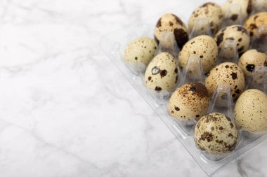 Beyaz mermer üzerinde plastik ambalajlı bıldırcın yumurtaları. Doğal ürünler. Mesaj için yer. taze yumurta