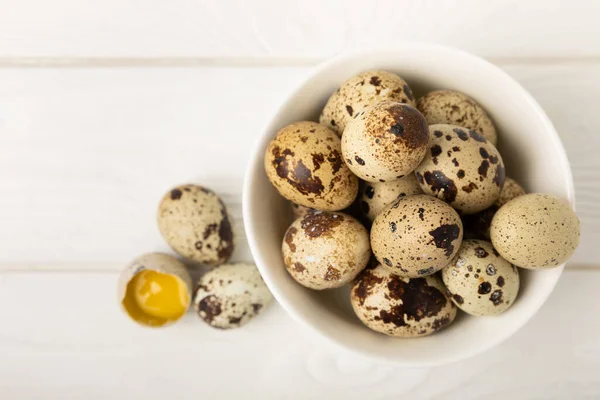 Quail eggs on a white texture background. Whole and broken quail eggs. Natural products. Place for text. Fresh quail eggs.
