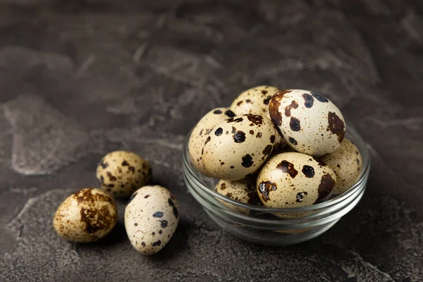 Quail eggs in a bowl on a black texture background. Natural products. Place for text. fresh eggs