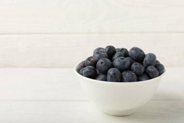 Beyaz desenli arka planda yaban mersini kasesi. Olgun ve taze yaban mersini. Vitaminler. Sağlıklı yemek. Meyve suyu. Uzayı kopyala Metin için yer