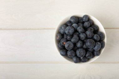 Beyaz desenli arka planda yaban mersini kasesi. Olgun ve taze yaban mersini. Vitaminler. Sağlıklı yemek. Meyve suyu. Uzayı kopyala Metin için yer