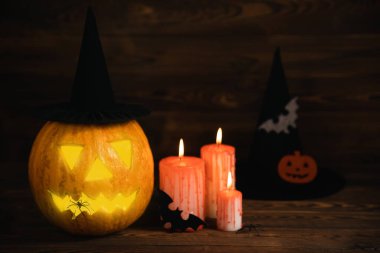 Kahverengi ahşap desenli Cadılar Bayramı balkabağı ve mumlar. Karanlık bir arka planda kompozisyon. Parlayan gözleri ve ağzı olan korkutucu bir kompozisyon. Tatil konsepti. Boşluğu kopyala