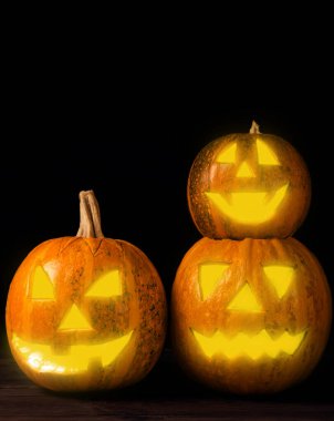 Kahverengi ahşap desenli Cadılar Bayramı balkabağı. Karanlık bir arka planda kompozisyon. Parlayan gözleri ve ağzı olan korkutucu bir kompozisyon. Tatil konsepti. Boşluğu kopyala