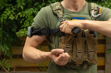 A military man holds a medical tourniquet in his hands to stop blood in first aid and prevent bleeding. Combat tactical equipment. Combat use Turnstile. clipart