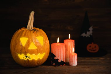 Kahverengi ahşap desenli Cadılar Bayramı balkabağı ve mumlar. Karanlık bir arka planda kompozisyon. Parlayan gözleri ve ağzı olan korkutucu bir kompozisyon. Tatil konsepti. Boşluğu kopyala