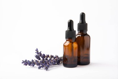 Cam şişede pipetli lavanta yağı. Beyaz arka planda izole edilmiş kokulu yağ ve lavanta çiçekleri olan şişe. Kopya alanlı lavanta yağı modeli. Serum.