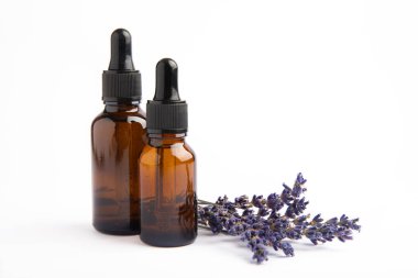 Cam şişede pipetli lavanta yağı. Beyaz arka planda izole edilmiş kokulu yağ ve lavanta çiçekleri olan şişe. Kopya alanlı lavanta yağı modeli. Serum.
