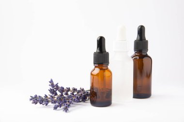 Cam şişede pipetli lavanta yağı. Beyaz arka planda izole edilmiş kokulu yağ ve lavanta çiçekleri olan şişe. Kopya alanlı lavanta yağı modeli. Serum.