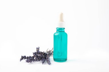 Cam şişede pipetli lavanta yağı. Beyaz arka planda izole edilmiş kokulu yağ ve lavanta çiçekleri olan şişe. Kopya alanlı lavanta yağı modeli. Serum.