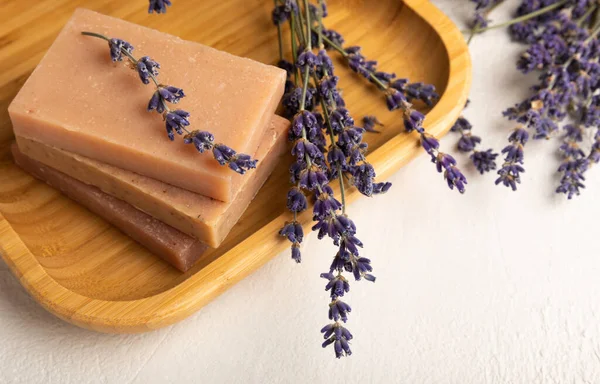 Lavender spa products and lavender flowers on white texture wood.SPA concept. Handmade soap on a bamboo stand, with lavender scent.Cosmetic treatment.Copy space.Place for text.Flat lay.